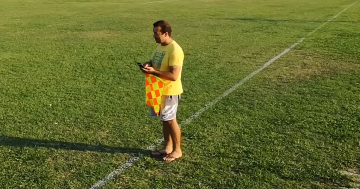 Επόπτης με σαγιονάρα και κινητό στο γήπεδο