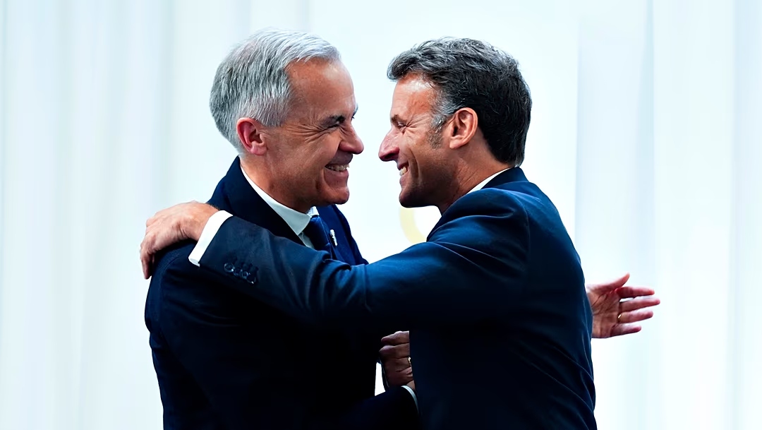 Mark Carney hugging Emmanuel Macron. Sean Kilpatrick/AP